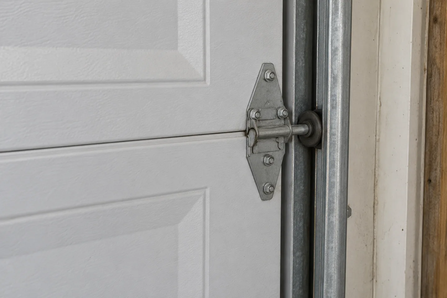 Representative installed roller and hinge beside a closed sectional door track